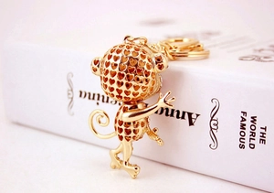Close-up of golden monkey keychain with heart-shaped cutouts on a white book surface