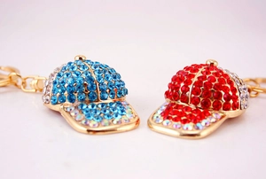 Close-up of blue and red rhinestone baseball cap keychains with gold-plated alloy rings