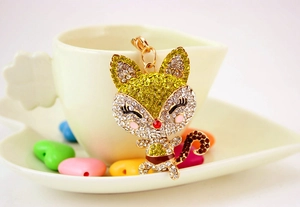 Close-up of golden cartoon fox keychain with rhinestones hanging on a ceramic cup