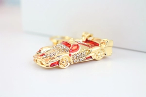Vue macro du porte-clés voiture de sport dorée avec émail rouge et strass brillants