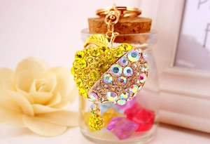 Detailed close-up of yellow rhinestone apple keychain hanging on a glass bottle