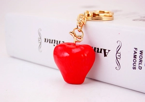 Close-up of a glossy red apple keychain charm with golden metal lobster clasp hardware