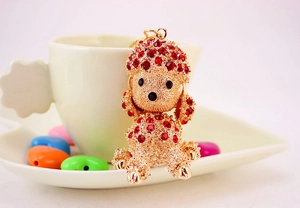 Detail of a golden poodle keychain featuring sparkling red rhinestones and a metal finish