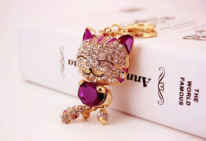 Gros plan détaillé d'un porte-clés chat doré de luxe avec cristal violet et strass blancs