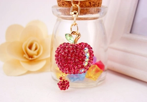 Close-up of sparkling rose pink rhinestone apple keychain with gold lobster clasp and leaf