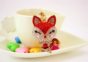Detailed macro view of a red rhinestone cartoon fox keychain with golden metal finish