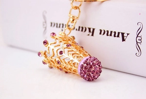 Vue détaillée d'un porte-clés couronne en métal doré serti de strass violets et ciselures