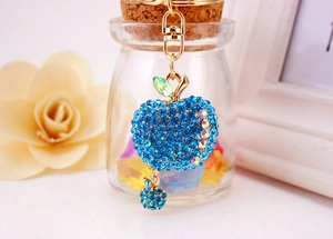 Close-up of sparkling blue rhinestone apple keychain with gold lobster clasp and leaves