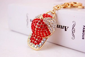 Detailed close-up of sparkling red and clear rhinestones on golden baseball cap keychain