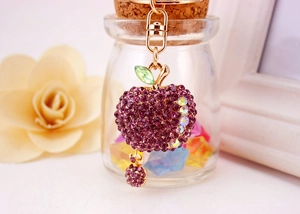 Detail of red rhinestone apple keychain with green crystal leaf and gold metal ring