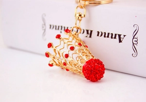 Détails d'un pendentif couronne dorée serti de strass rouges avec un fermoir mousqueton