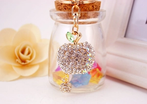 Close-up of sparkling rhinestone apple keychain with gold metal clasp and green leaf detail