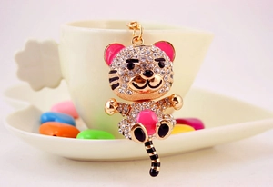 Close-up of golden tiger keychain with sparkling rhinestones hanging on a coffee cup
