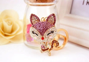Macro shot of cartoon fox keychain with purple crystals and gold metal finish