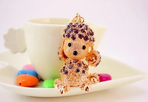 Detailed macro of a purple rhinestone poodle car keychain with gold plating and black eyes