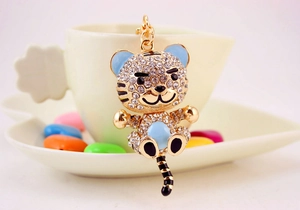 Detail of cute tiger keychain with white rhinestones and blue enamel on gold metal base