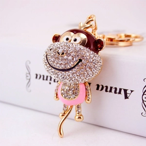 Cute golden monkey keychain with sparkling white rhinestones and pink enamel finish