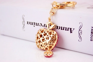 Close-up of golden apple keychain featuring sparkling red rhinestones and hollow-out carving