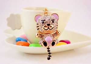 Close-up of cute cartoon tiger keychain with sparkling rhinestones on a white ceramic cup
