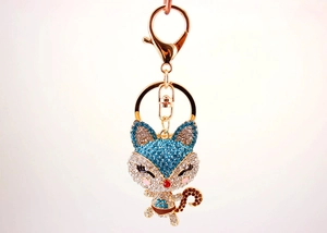 Close-up of sparkling diamond-encrusted fox keychain with blue rhinestones and gold plating