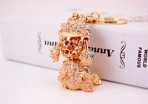 Detailed close-up of golden poodle keychain with blue rhinestones and textured metal alloy