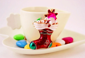 Macro view of Christmas stocking brooch with enamel and pearls hanging on a white coffee cup