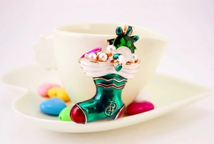 Detailed view of a green enamel Christmas stocking brooch with pearls and crystals