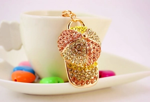 Macro detail of a rhinestone baseball cap keychain in gold finish on a white cup