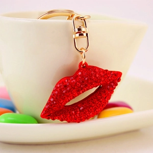 Sparkling red lip keychain with rhinestones and gold lobster clasp on white ceramic cup