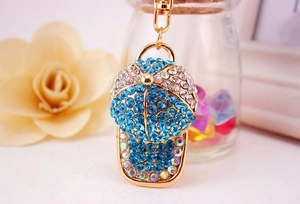 Macro shot of baseball cap keychain with blue and white rhinestones on golden alloy