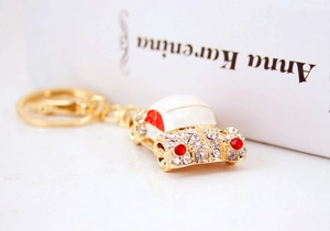 Detail of vintage car keychain with white enamel and sparkling rhinestones on gold metal
