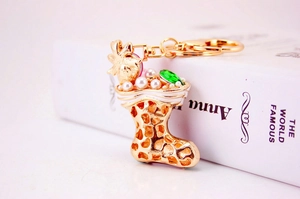 Detail of golden Christmas stocking keychain with white pearls and a green gemstone charm