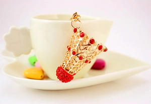 Gros plan d'un porte-clés de badminton doré avec strass rouges sur une tasse blanche