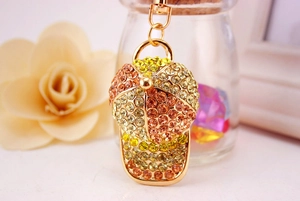 Close-up of golden baseball cap keychain with orange rhinestones and metallic clasp