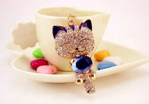 Détail d'un porte-clés chat doré orné de strass blancs et d'une grande pierre bleue