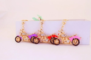 Detailed macro view of crystal motorcycle keychains in purple, red, and pink gold plating