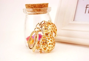Détail du porte-clés gourde dorée avec motifs de cœur évidés et pendentif flocon de neige