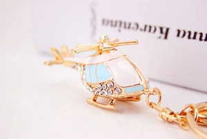 Macro detail of golden helicopter keychain with sparkling rhinestones and blue enamel work
