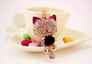 Détail du porte-clés chat de la fortune avec cristaux violets sur une tasse blanche