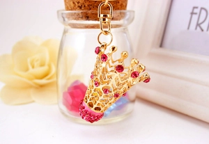 Détail d'un porte-clés couronne dorée avec strass roses sur un élégant fond de cadeau décoratif