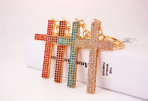 Detail of four colorful rhinestone-encrusted cross keychains with golden metal bases