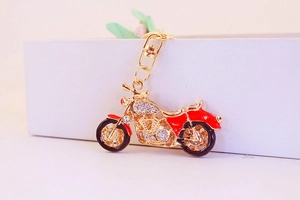 Macro view of golden motorcycle keychain with white rhinestones and red enamel details