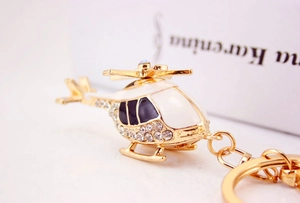 Detail of a gold plated helicopter keychain with white enamel and sparkling rhinestones