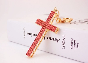 Detail of pink rhinestone cross keychain with golden lobster clasp on book background