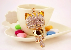 Détail d'un porte-clés chat mignon doré avec strass scintillants et une grande pierre jaune