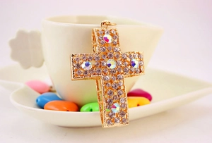 Détail du pendentif croix dorée orné de strass brillants et de cristaux colorés AB
