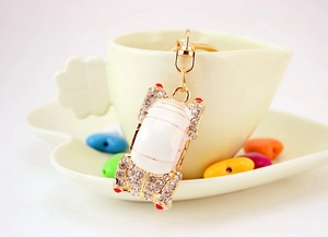 Detailed view of a gold car keychain with white rhinestones on a ceramic cup edge