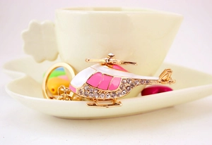 Close-up of golden helicopter keychain with sparkling crystals and pink enamel details