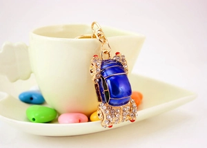 Detailed close-up of blue enamel car keychain with sparkling rhinestones on coffee cup