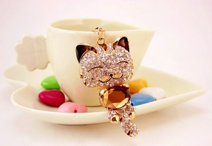Détail de porte-clés chat porte-bonheur doré avec strass brillants et cristal ambré